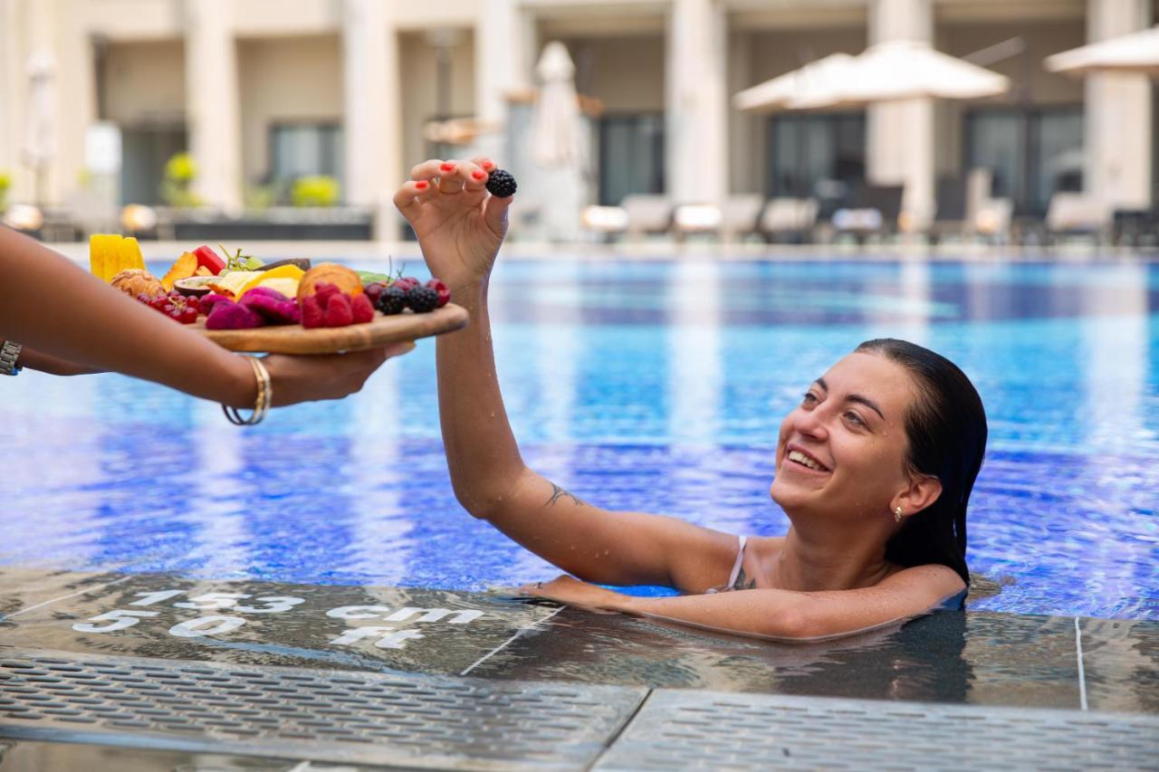 Triumph Luxury Hotel Каир Экстерьер фото A woman being served fruit in a swimming pool